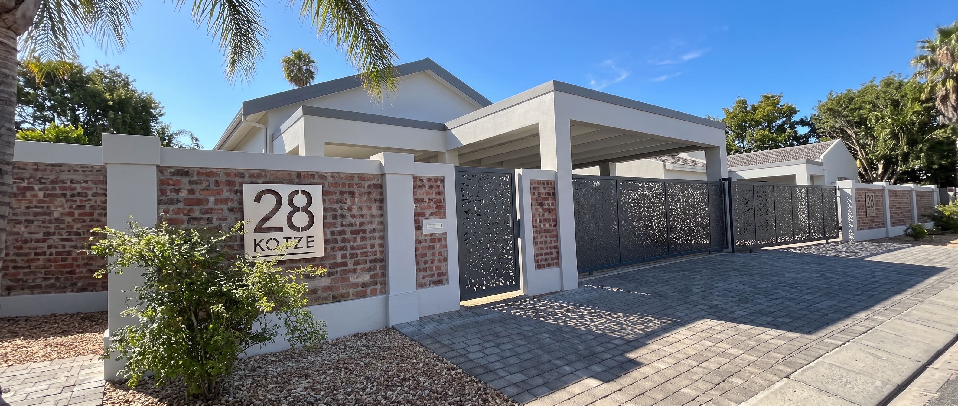 Illuminated House Exterior with Custom Gate and Sign